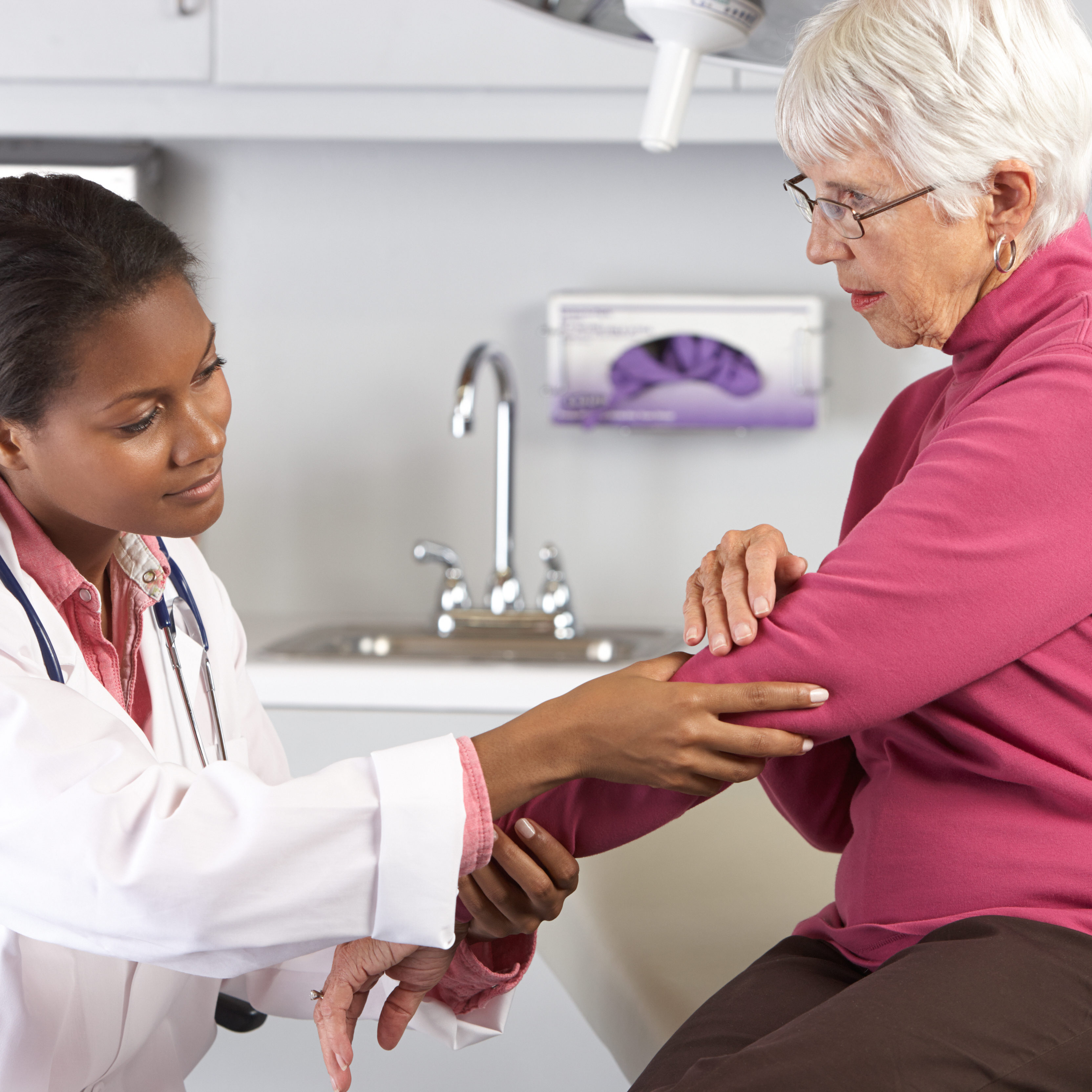 Female Doctor Examining Female Patient With Elbow Pain